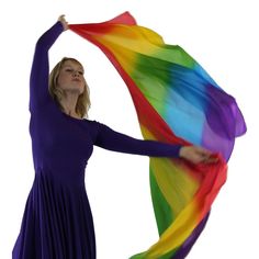 a woman in a blue dress holding a rainbow colored scarf