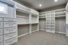 an empty room with white shelves and drawers