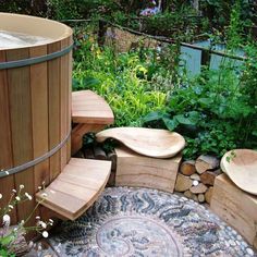 a wooden bench sitting next to a hot tub in the middle of a lush green garden