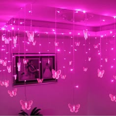 a room with pink lights and butterflies hanging from the ceiling