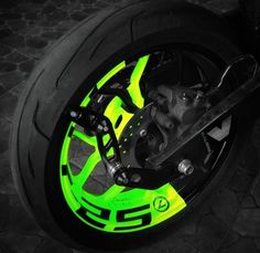 the front wheel of a motorcycle lit up with neon green paint and black spokes