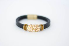 This Regal Leather Bracelet is fit for a queen—or anyone with a sense of style. The dazzling gold and ivory swirled bead is set off on a flat black leather, making it a perfectly elegant accessory. Plus, the magnetic clasp makes it easy to put on ... Elegant Leather Bracelets With Gold Clasp, Elegant Leather Bracelet With Gold Clasp, Elegant Adjustable Leather Bracelet With Magnetic Closure, Elegant Leather Jewelry With Gold Clasp, Luxury Leather Bracelet With Gold Clasp, Elegant Gold Leather Bracelet For Formal Occasions, Elegant Adjustable Bracelet With Gold Clasp, Elegant Gold Leather Bracelet, Elegant Adjustable Leather Bracelets