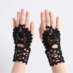 a woman's hands with black crocheted lace on them, both holding their fingers together