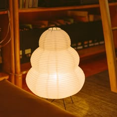 a lamp sitting on top of a wooden floor next to a book shelf filled with books