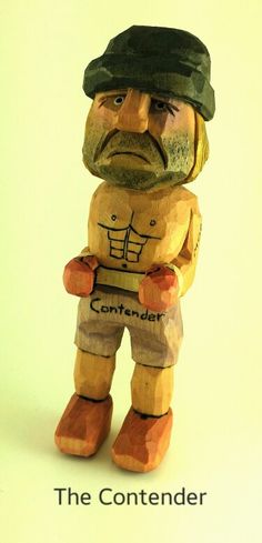 a wooden statue of a man with a hat and beard holding a sign that says the contenter