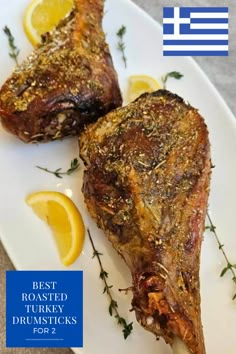 two pieces of meat sitting on top of a white plate with lemons and herbs