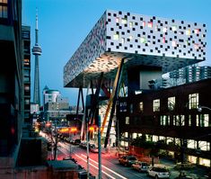 an unusual building in the middle of a busy city street at night with cars passing by