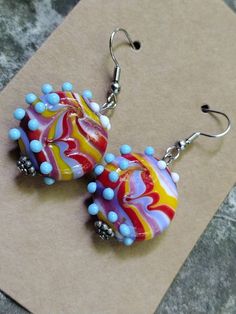 a pair of colorful glass beaded earrings sitting on top of a piece of paper