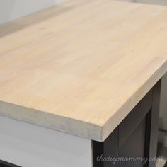 a wooden counter top sitting on top of a white countertop next to a stove