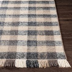 a plaid rug with fringes on the floor