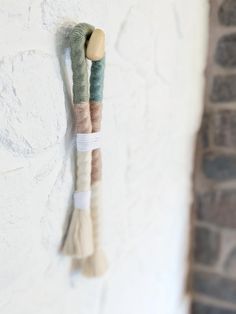 two pieces of fabric hanging on the wall next to a brick wall with a wooden hook