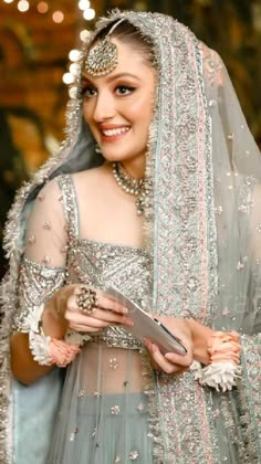 a woman in a bridal gown and veil smiles at the camera while holding a piece of paper