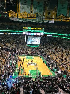 a basketball game in progress with the crowd watching from the upper level seats and people standing on the sidelines