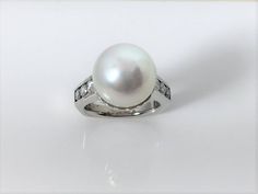 Beautiful almost perfectly round South Sea Cultured Pearl set in a 18k white gold ring with diamonds on the shank. Perfect for everyday wear but also that finishing touch on a special occasion outfit. Pearl measures 13.0 mm round Diamonds weigh approximately .66tw Ring size: 5 3/4 Classic White Pearl Ring With Diamond Accents, Timeless White Gold Pearl Ring With Diamond Accents, Timeless White Gold Pearl Ring With Diamonds, Timeless Diamond-white Pearl Ring With Diamond Accents, Timeless Pearl Ring With Diamond Accents For Formal Occasions, Classic White Gold Pearl Ring With Diamond Accents, Timeless Diamond White Pearl Ring With Diamond Accents, Luxury Pearl Ring With Brilliant Cut For Formal Occasions, Formal Pearl Ring With Diamond Accents And Cubic Zirconia