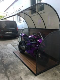 a purple motorcycle is parked in front of a white building with a brown wooden platform