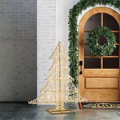 a white christmas tree sitting next to a wooden door with a wreath on the top