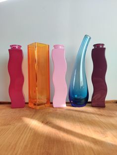 five different colored vases are lined up on the floor