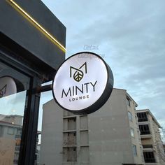 the sign for minty lounge is hanging on the side of the building in front of it