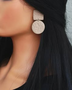 a woman with long black hair wearing large white and silver earrings on her earring