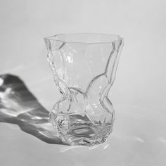 a clear glass vase sitting on top of a white countertop next to a shadow