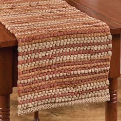 a close up of a wooden table with a woven runner on the top of it