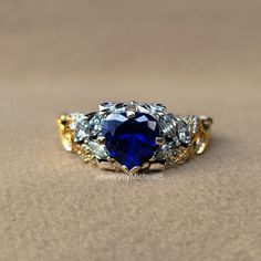 Welcome to our shop "JewelrybyMichealB"  ● Victorian Style Wedding Ring Heart Cut Blue Sapphire Bridal Ring 14k Two tone Gold Ring Unique Leaf Style Engagement Ring Anniversary Gifts  Item Description and specifications: ● Design Code : PEBRM-18 ● Main Stone Details  -  Type      :- Sapphire (Lab Created) -  Shape   :- Heart Cut  -  Size       :- 7 mm. (± 0.20) - Weight   :- 1.13 Ct (Diamond Equivalent) -  Color     :- Blue -  Clarity   :- VVS-VS ● Side Stone Details  -  Type      :- CZ - High Quality -  Shape   :- Round & Marquise Cut  - Weight   :- 0.45 Ct (Diamond Equivalent) -  Color     :- Colorless -  Clarity   :- VVS-VS ● Metal Details - Metal type: Silver, Gold, Platinum - Metal Purity: 925, 10k, 14k, 18k - Metal Tone: White, Rose, Yellow - Metal Stamp: Yes ● 𝗖𝘂𝘀𝘁𝗼𝗺𝗶𝘇𝗲 𝗢? Blue Diamond Heart Ring For Wedding, Blue Multi-stone Round Cut Jewelry, Blue Sterling Silver Heart Ring For Wedding, Blue Heart-shaped Jewelry With Prong Setting, Blue Heart Ring For Wedding Fine Jewelry, Blue Gemstone Heart Ring For Wedding, Blue Heart Cut Jewelry With Accent Stones, Blue Multi-stone Wedding Birthstone Ring, Blue Multi-stone Birthstone Ring For Wedding