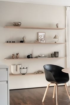 a dining room table with chairs and shelves on the wall