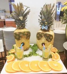 two pineapples are sitting on top of orange slices with glasses in front of them