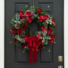 a christmas wreath with pine cones and poinsettis is hanging on the front door