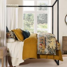 a bedroom with a four poster bed and white curtains on the window sill above it