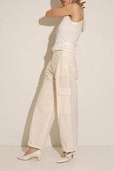 Loosely tailored cargo pant in a soft yet structured cotton. Straight leg with tie at ankle, cinch for a more tapered silhouette. Side pockets and oversized patch pockets above knee. Made in New York City. Fabric is 100% cotton. Ella is 6' tall, 35" bust, 26" waist, 36" hip, and is wearing a size S. Workwear Wide-leg Cargo Jeans With Side Pockets, Beige Cotton Cargo Jeans With Patch Pockets, Wide-leg Parachute Pants With Side Pockets For Work, Cotton High-waisted Pants With Flap Pockets, Beige Cotton Pants With Flap Pockets, Spring Cotton Cargo Pants With Side Pockets, Spring Cotton Cargo Pants With Cargo Pockets, High-waisted Cotton Cargo Jeans For Work, High-waisted Relaxed Fit Cargo Pants With Patch Pockets