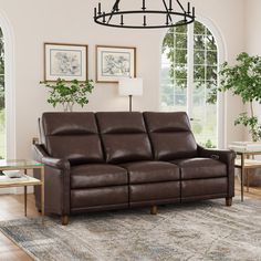 a living room scene with focus on the leather sofa and reclining chair, coffee table and potted plant