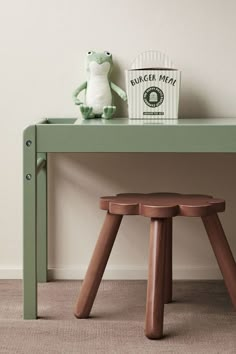 a green table with two stools and a stuffed frog