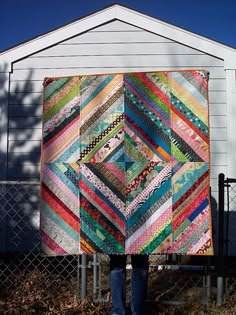 a person standing in front of a fence with a quilt on it