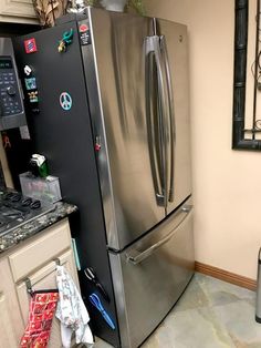 a stainless steel refrigerator in a kitchen next to a trash can and garbage can on the floor