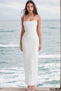 a woman standing on the beach in a white dress