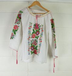 Women's Vintage Indian Blouse | Embroidered | A Condition Description Hungarian style summer blouse featuring embroidered arms and chest. Sleeves and neck fasteners. Great wardrobe staple for Summer. Made in India. Material - Cotton Brand - unbranded  Size -  see measurements   Measurements lying flat Waist - 52cm Bust - 50cm  Length - 66cm  Sleeve Length - 58cm from side neck  This is a vintage item sourced and inspected in Melbourne, Australia. Items have been washed and cared for. Please note Long Sleeve Tops With Floral Embroidery For Summer, Summer Cotton Top With Embroidered Sleeves, Long Sleeve Tops With Geometric Embroidery For Summer, Long Sleeve Embroidered Top With Floral Design For Summer, Folk Style Long Sleeve Summer Tops, Folk Style Embroidered Long Sleeve Tops, Summer Casual Peasant Top With Intricate Embroidery, Summer Cotton Peasant Top With Embroidered Sleeves, Traditional Long Sleeve Peasant Top For Summer