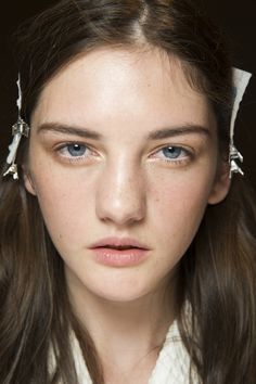 a woman with long brown hair and blue eyes is looking at the camera while wearing white clothing