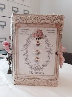 an ornate frame with roses on it sitting on top of a white tablecloth covered table