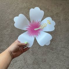 a hand holding a paper flower with pink and white petals