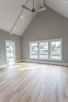 an empty room with white walls and wood floors is shown in this image, there are two windows on the far side of the room