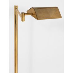 an antique brass swing arm lamp with a white back ground and light from the early 1900's