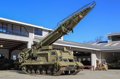 an army vehicle parked in front of a building with a large missile on it's back