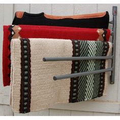 three towels hanging on a towel rack in front of a white door with black handles