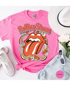 Step back in time and rock out in style with our Vintage Flower Rolling Stone Tee! 🌸🎸 This retro-inspired t-shirt features a classic Rolling Stone logo beautifully intertwined with vibrant flowers, capturing the free-spirited essence of rock 'n' roll and the timeless charm of the 70s. 🌼✨ Crafted from super-soft, high-quality fabric, this tee offers ultimate comfort and a perfect fit, making it an essential addition to your wardrobe. Whether you're heading to a concert, a festival, or just channeling your inner rock star, this tee will have you looking effortlessly cool and totally groovy. 🌟👕 Get ready to roll and bloom with style! 🌿🎶🛒 Retro Pink Printed T-shirt, Spring Festival Hippie T-shirt, Spring Fan Merchandise Screen Print Top, Casual T-shirt For Spring Festival, Casual Spring Festival T-shirt, Retro Graphic Print T-shirt For Spring, Spring Festival Relaxed Fit T-shirt, Graphic Tee For Spring Music Festival, Hippie Graphic Print Top For Music Festival