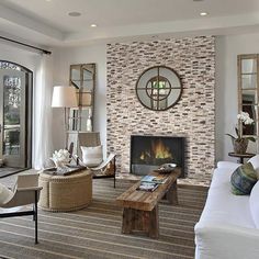 a living room filled with furniture and a fire place in front of a stone wall