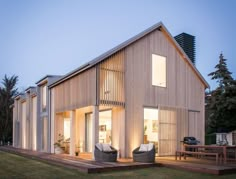 a house that is made out of wood and has two chairs on the front porch