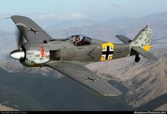 a fighter jet flying through the air with mountains in the background