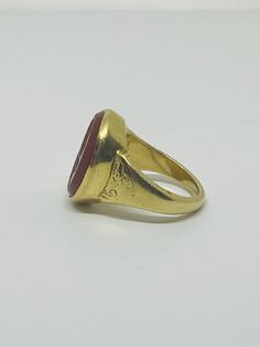 "This is a vintage 18K (high-karat) yellow gold Cameo-design statement ring. Definition of a \"cameo\": a piece of jewelry, typically oval in shape, consisting of a portrait in profile carved in relief on a background of a different color. Material(s): 18K yellow gold + unidentified material (cameo) Total weight: 12.2 grams Flaws (if any): None to mention Marking(s): \"18ct\" (translating to 18K gold) Measurements: The face of the ring measures 17.9 millimeters in height by 5.8 millimeters in wi Vintage 14k Gold Cameo Rings, Formal Gold Cabochon Signet Ring, Classic Yellow Gold Signet Ring With Cabochon, Gold Ruby Ring With Cabochon In 14k Gold, 14k Gold Ruby Cabochon Ring, Antique 14k Stamped Jewelry For Ceremonial Occasions, Gold Heirloom Signet Ring With Cabochon, Antique Yellow Gold Ruby Ring With Polished Finish, Heirloom Gold Signet Ring With Cabochon