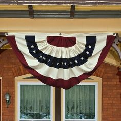 an american flag hanging from the side of a brick building with two doors and windows